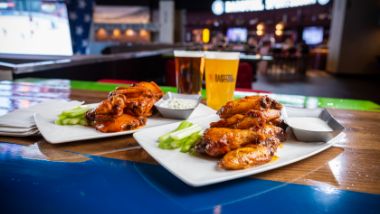 Chicken wings and beer sitting on a table.