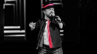 Brad Williams with black background in red tie and hat