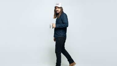 Dusty Slay holding a coffee cup with gray background