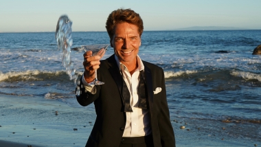 Richard Marx in tuxedo holding a martini glass at the beach