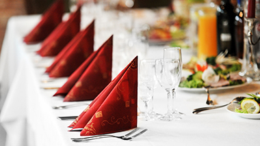 Banquet table with elegant table setting with linens napkins glasses and silverware