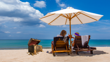 people at the beach in beach chairs, clinking drinks